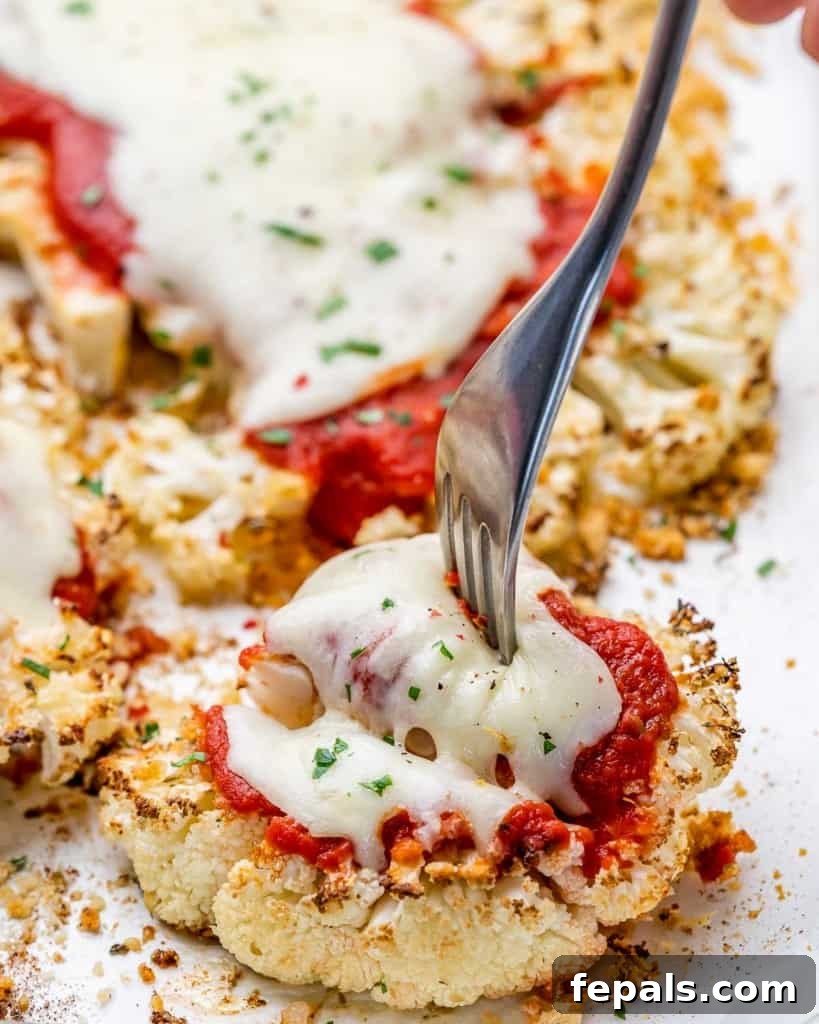 fork on a baked cauliflower steak topped with melted cheese