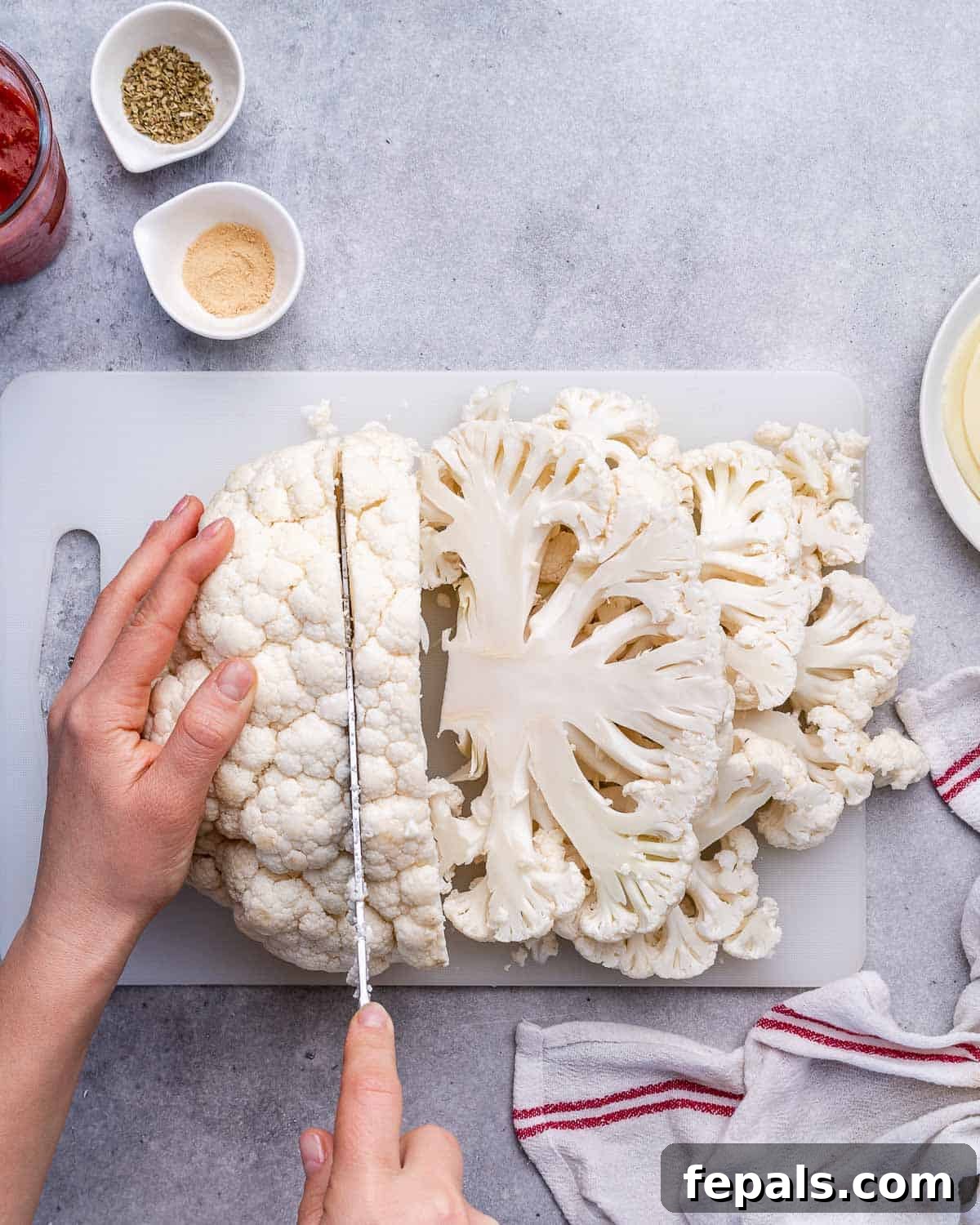 hand holding knife and slicing through a cauliflower