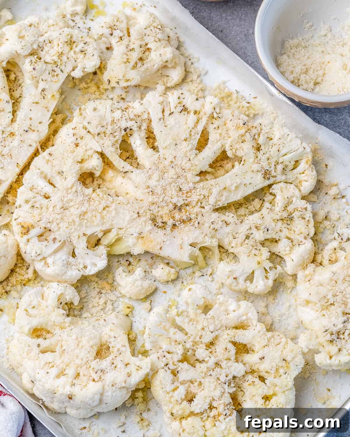 cauliflower steaks over a pan topped with parmesan cheese and breadcrumbs before baking