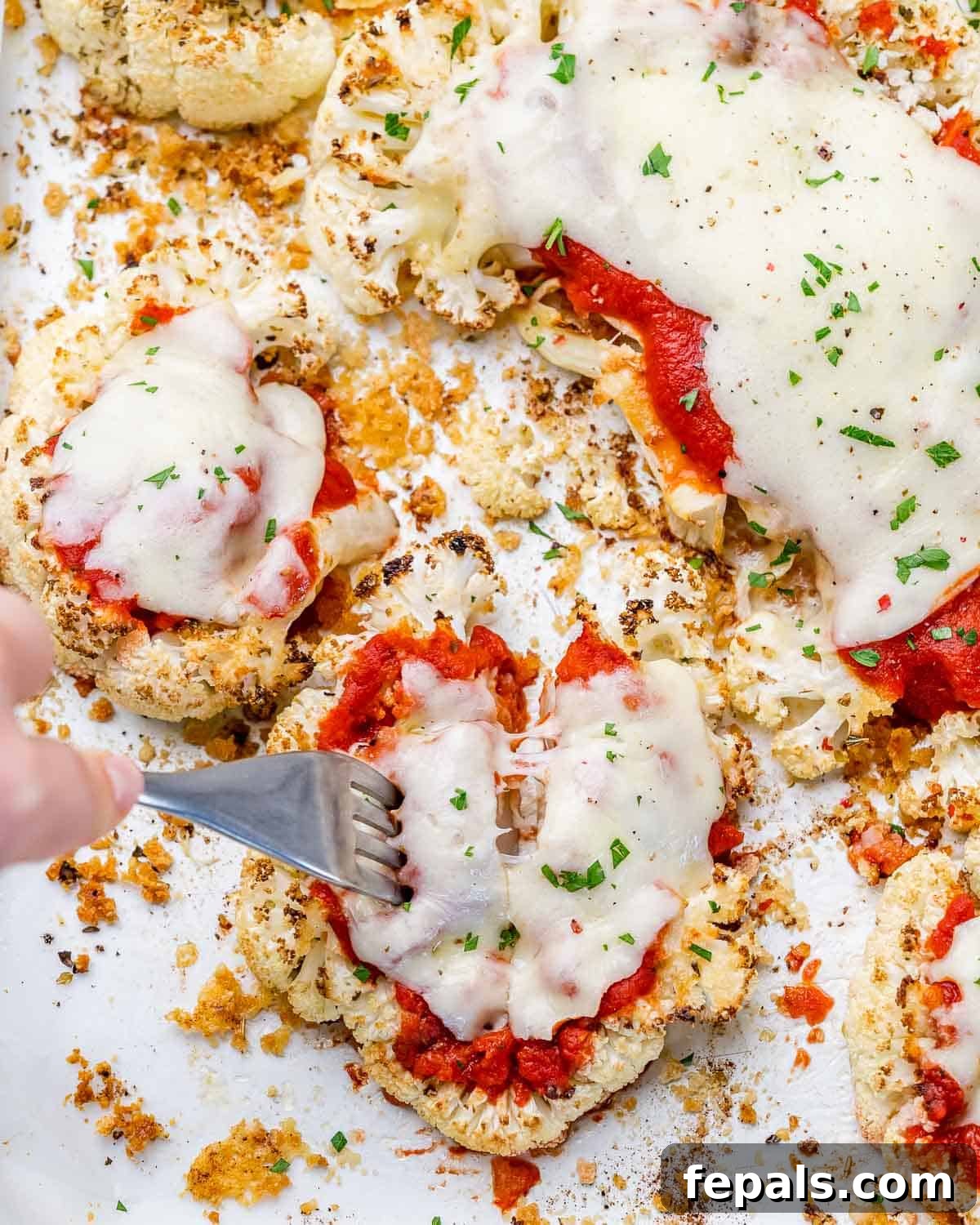 hand holding fork and grabbing a bite of baked cauliflower