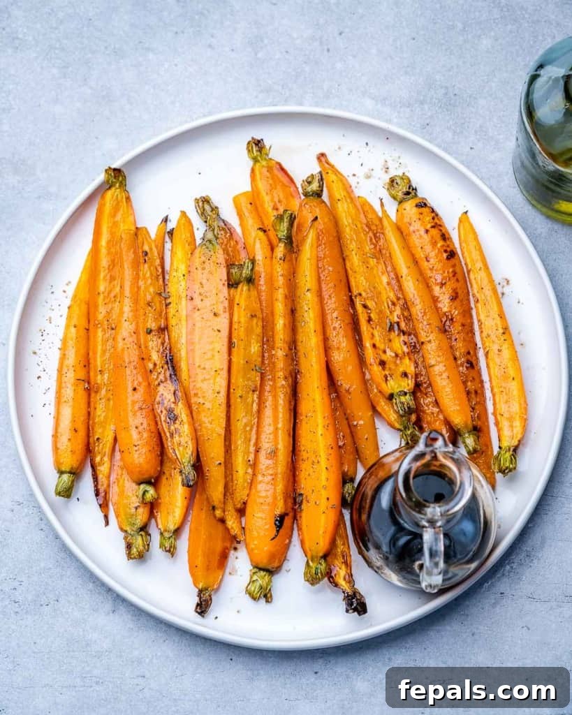 Honey-Kissed Balsamic Roasted Carrots 2 Glazed carrots on a white plate with balsamic vinegar.