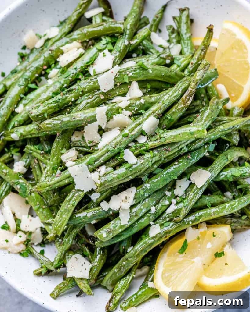 close up green beans topped with shaved cheese and lemon wedges 