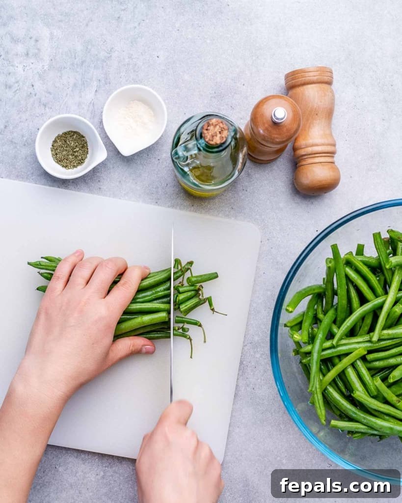 hand cutting the trims off green beans on a white cutting board