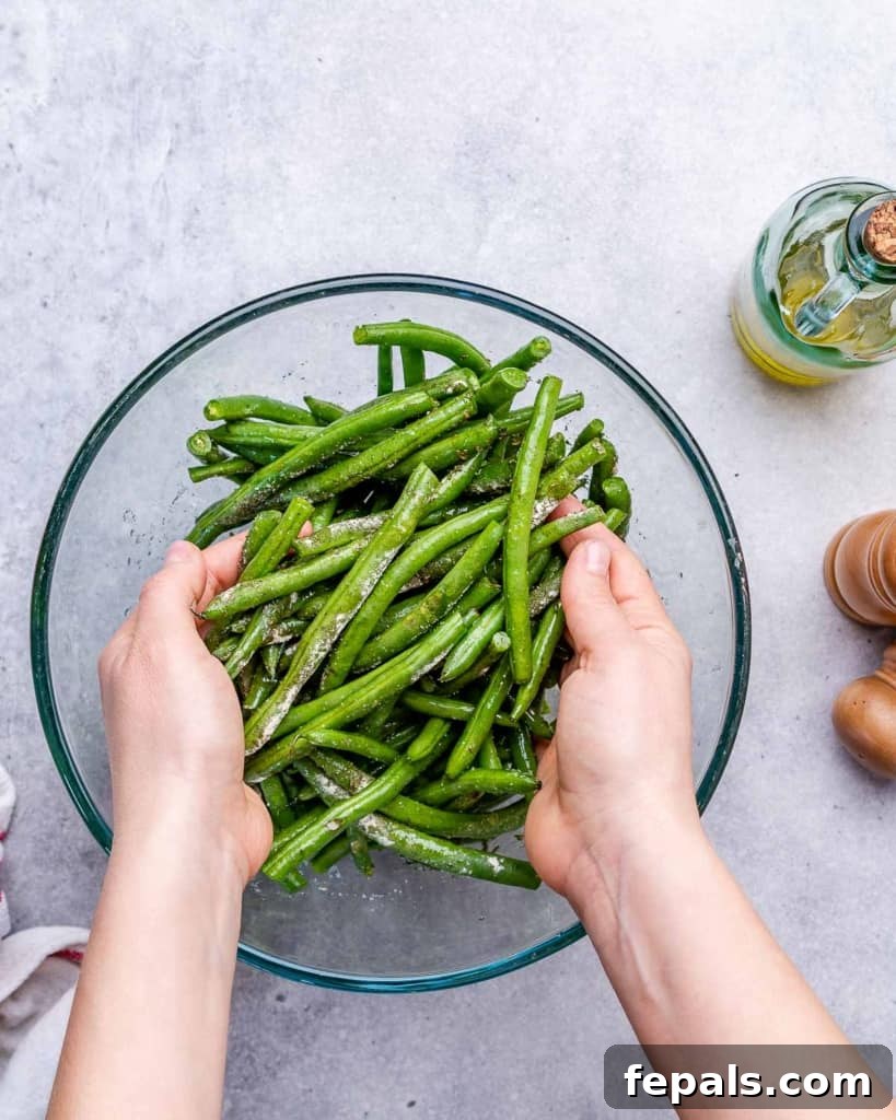 hand tossing the green beans in a bowl