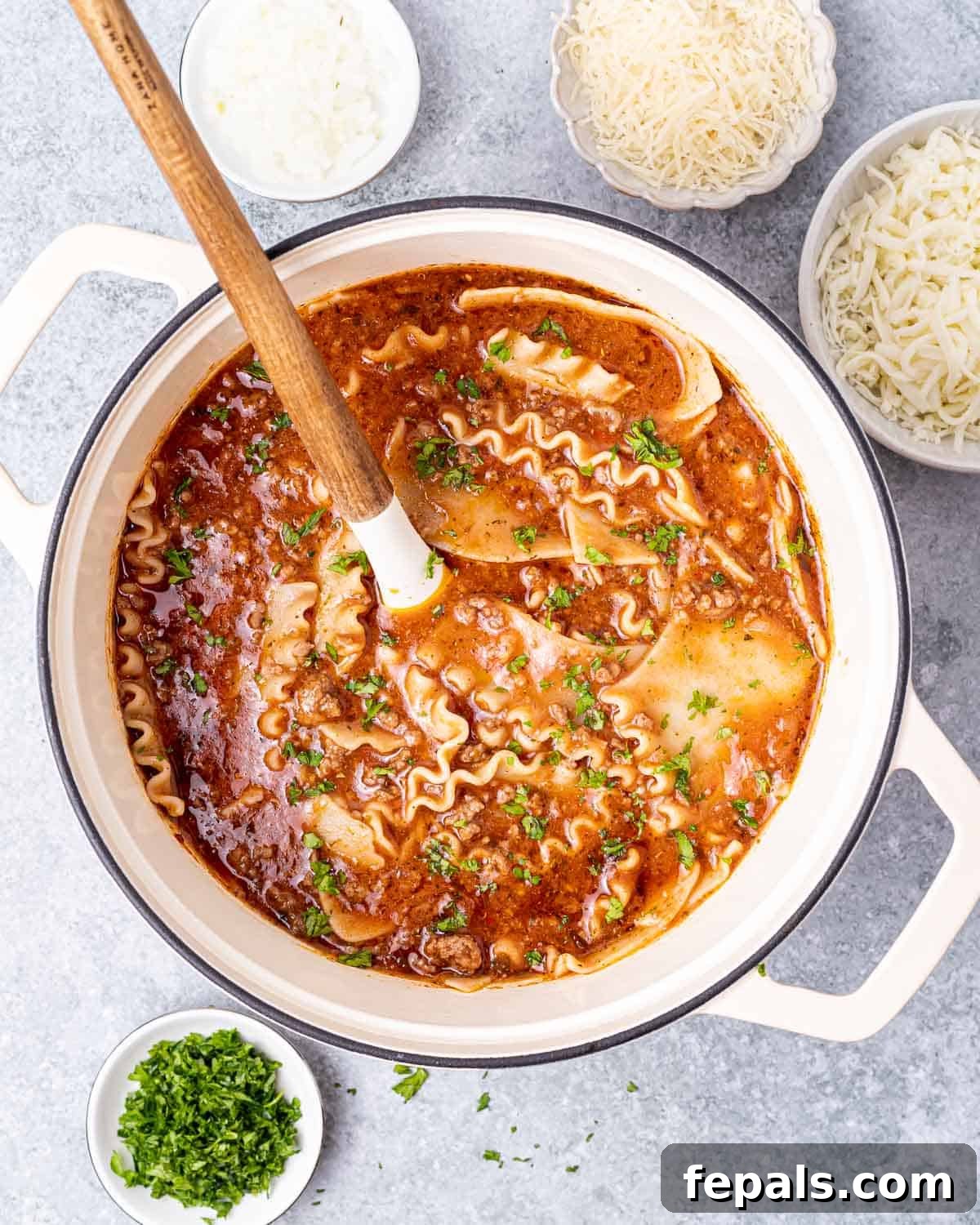 Hearty Lasagna Soup 8 A large wooden spoon stirring the rich, simmering lasagna soup in a Dutch oven, with melted cheese and tender noodles visible.