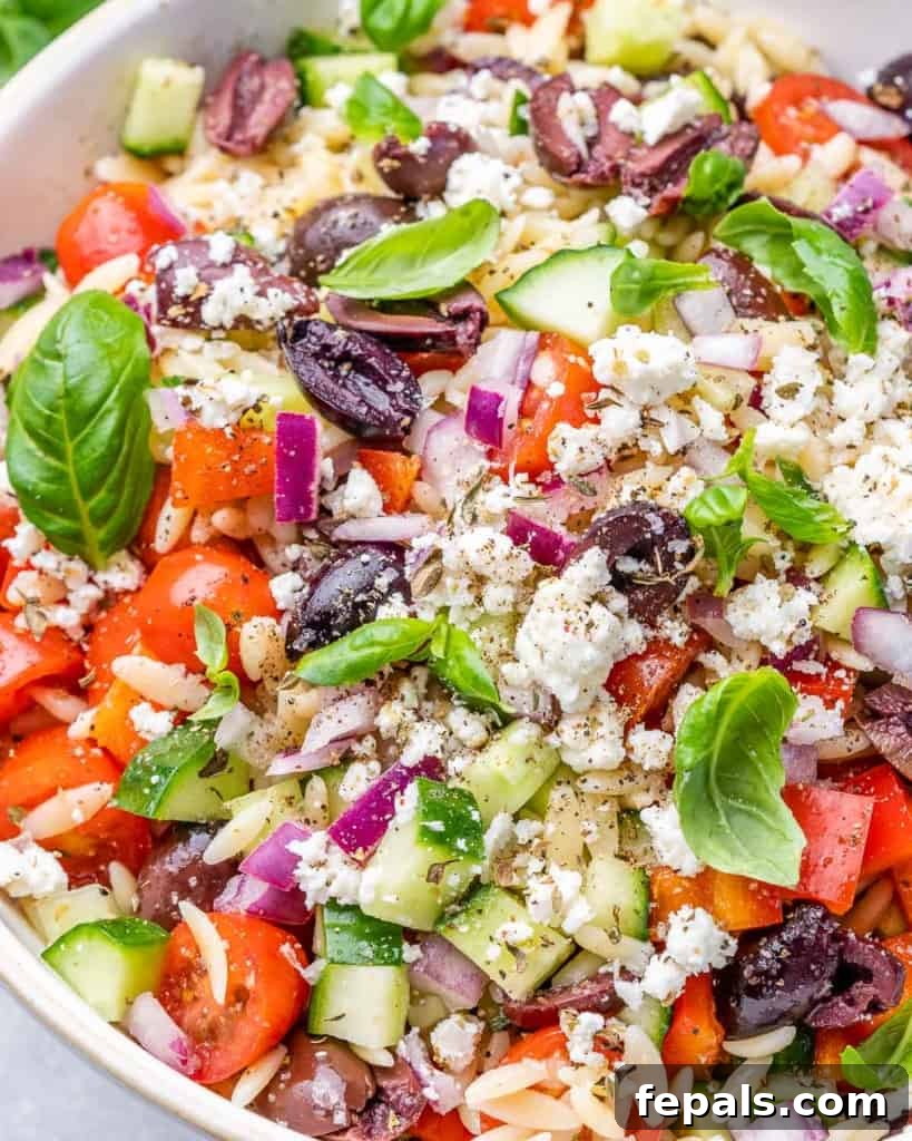 Zesty Greek Orzo Salad 3 Close-up of Greek Orzo Pasta Salad, highlighting tomatoes, orzo, feta, and fresh herbs in a white bowl.