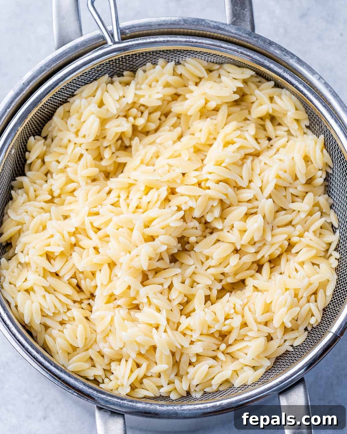 Zesty Greek Orzo Salad 5 Close-up shot of cooked orzo pasta in a pot, ready for draining.