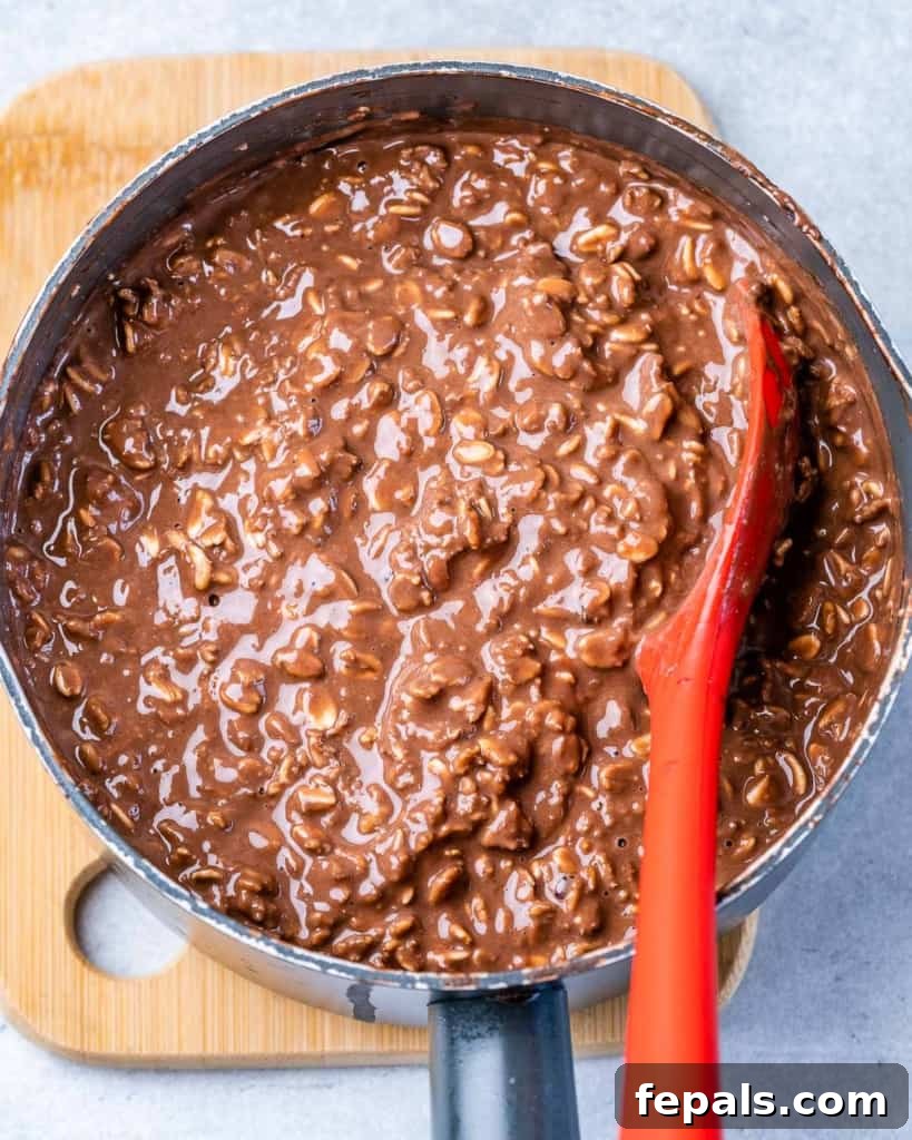 miked chocolate oatmeal in a pot with red spoon in pot to mix the oatmeal