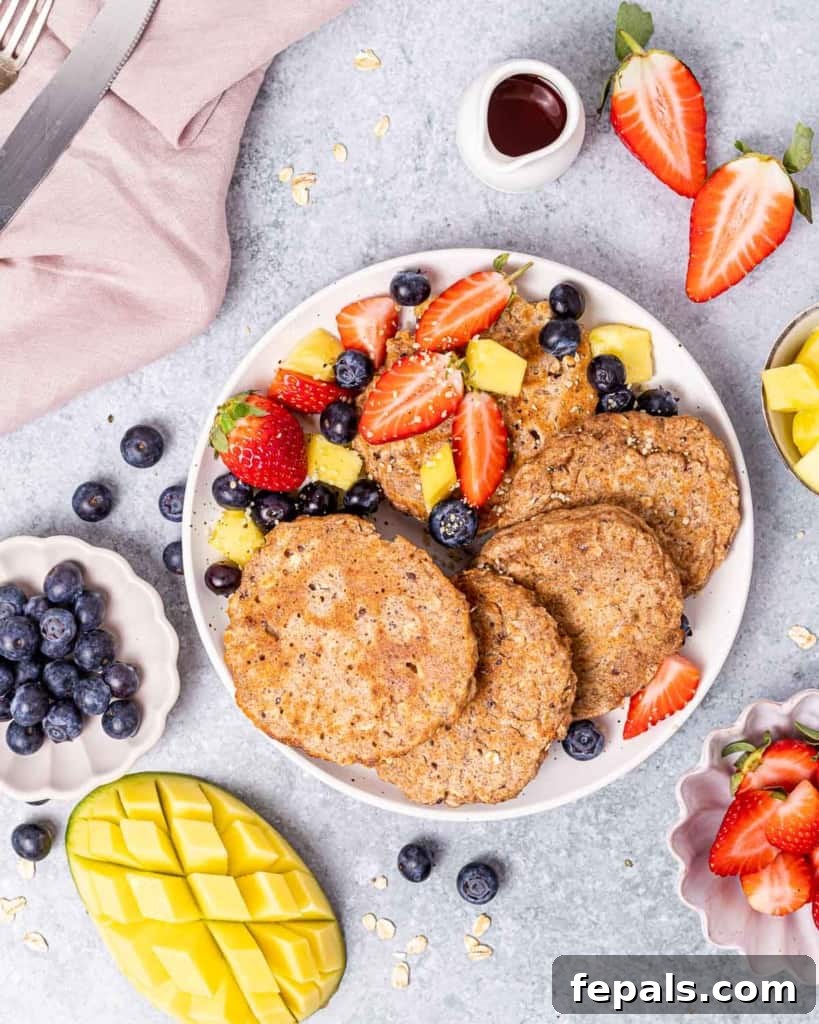 Pancakes on a white plate with fresh fruit.