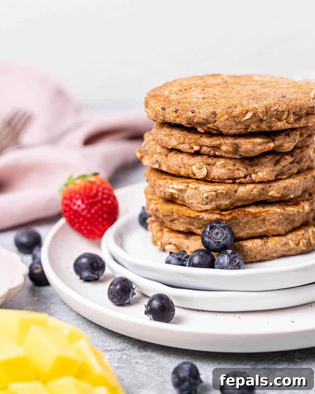 Stacking pancakes to serve on a white plate.