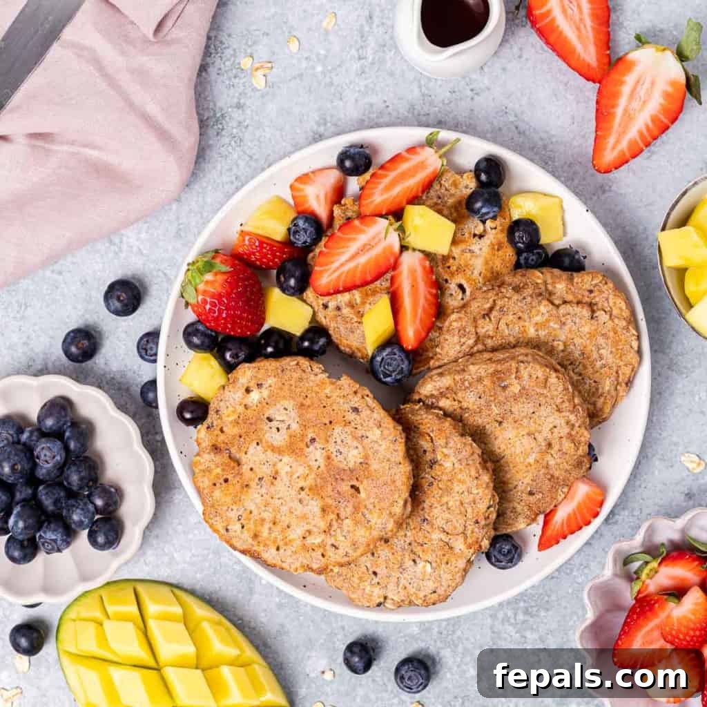 Pancakes on a white plate with fresh fruit.