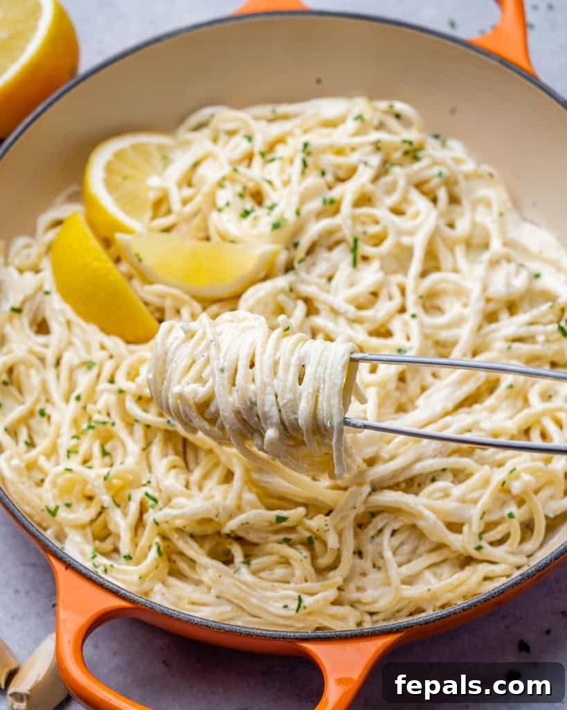 Luscious Vegan Lemon Pasta 2 Tong grabbing pasta from an orange skillet, highlighting its creamy texture.