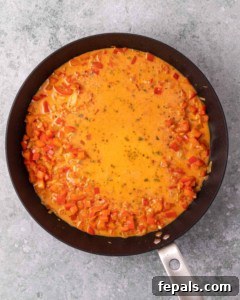 Skillet Peri Peri Chicken: Creamy & Zesty 18 Simmering a creamy red sauce in a skillet.