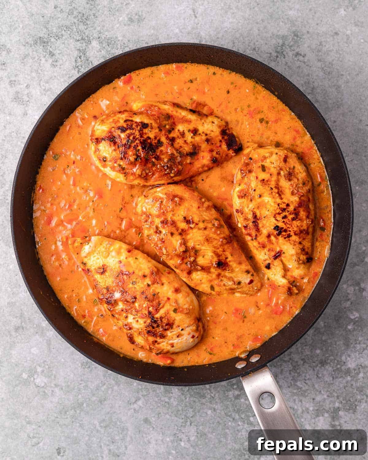 Skillet Peri Peri Chicken: Creamy & Zesty 9 Chicken breasts returning to simmer in the creamy peri peri sauce within a pan.