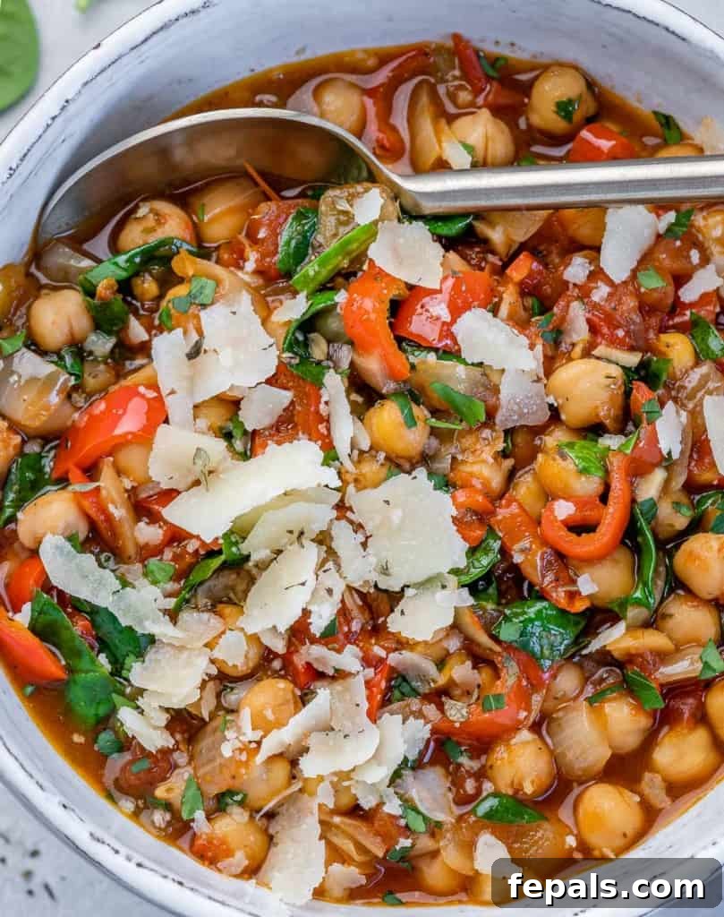 Savory Chickpea and Vegetable Simmer 11 A bowl of vegetarian chickpea stew, generously garnished with shaved Parmesan cheese and fresh green herbs, presented beautifully for serving.