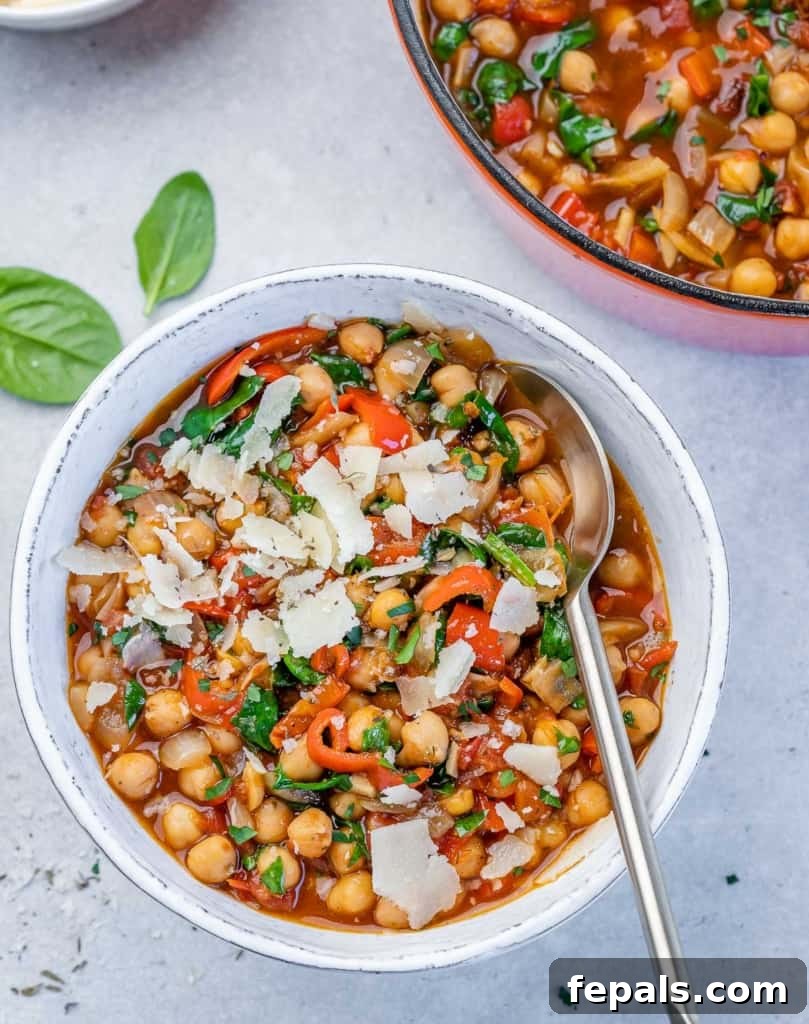 Savory Chickpea and Vegetable Simmer 3 A close-up of a vibrant chickpea stew, showcasing the chickpeas, red peppers, and green spinach in a flavorful broth.