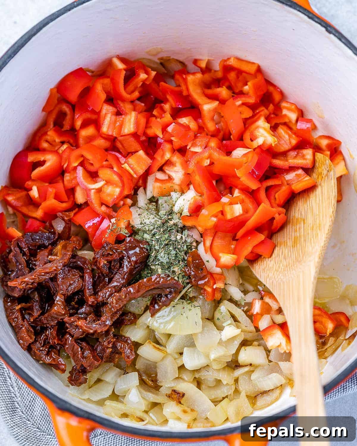 Savory Chickpea and Vegetable Simmer 6 Adding garlic, mini peppers, sun-dried tomatoes, and Italian seasoning to sautéed onions in a Dutch oven, stirring to combine.