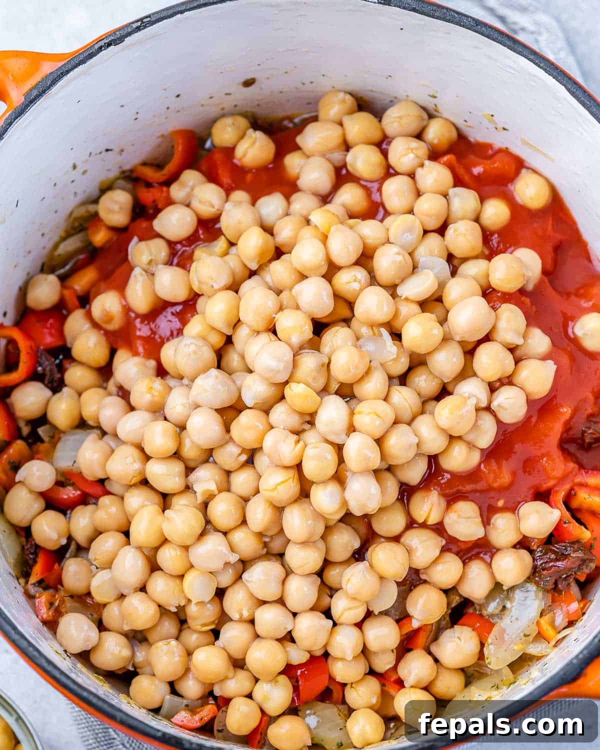 Savory Chickpea and Vegetable Simmer 7 Pouring canned diced tomatoes, vegetable stock, balsamic vinegar, and chickpeas into the pot, preparing the stew for simmering.