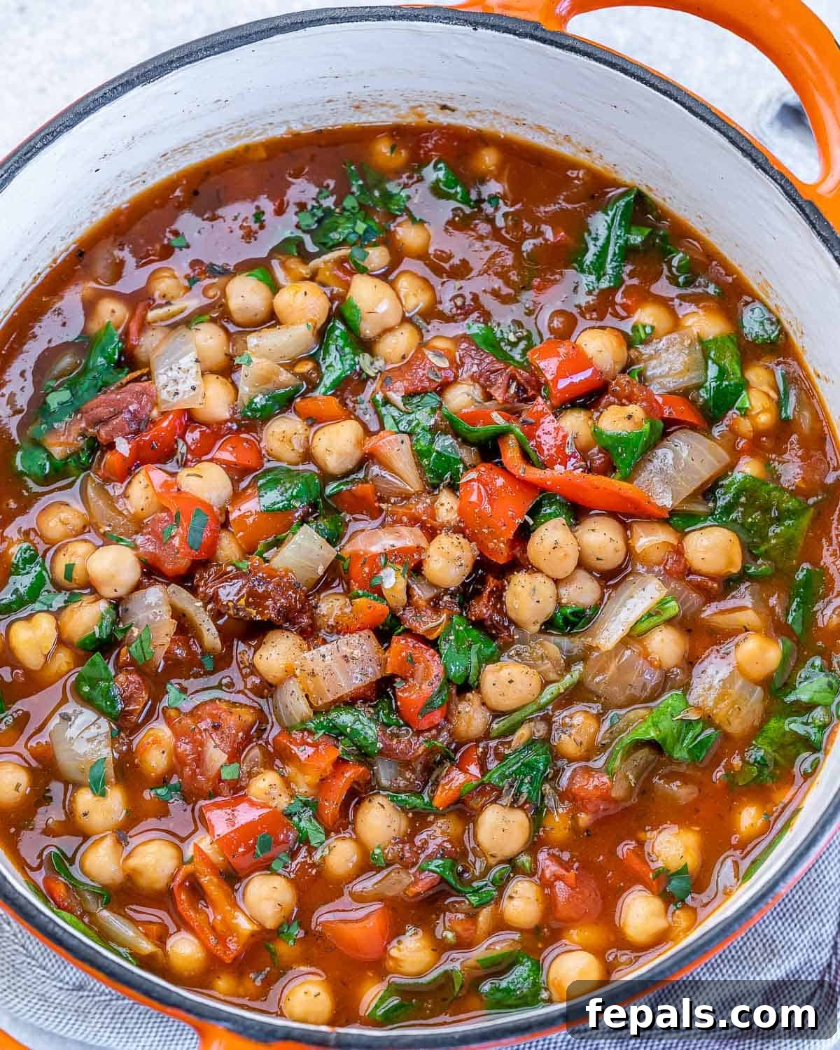Savory Chickpea and Vegetable Simmer 8 Fresh spinach being stirred into the simmering chickpea stew in a Dutch oven, adding a final touch of color and nutrients.