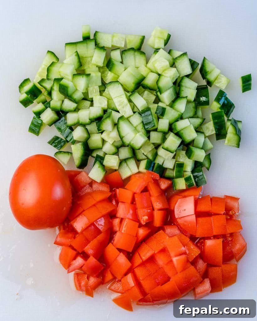 Tuscan Kale Power Jar 4 Freshly chopped tomato and cucumber on a wooden cutting board, prepped for a salad.