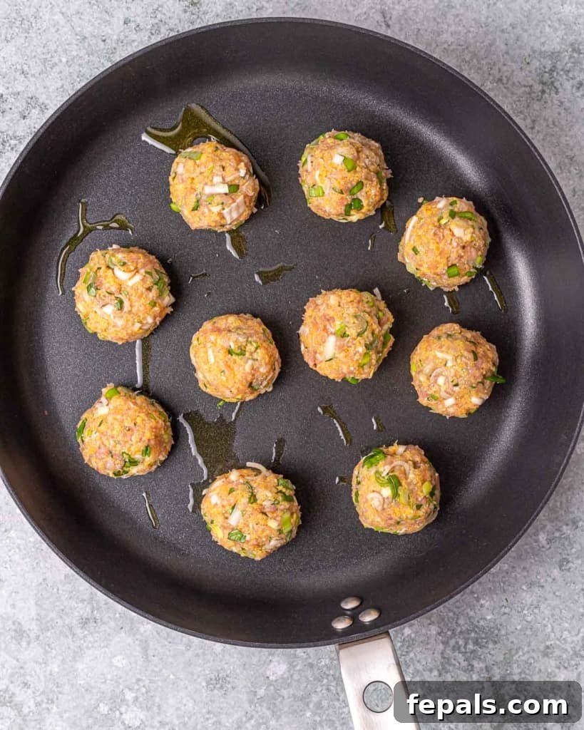 Savory Garlic Chicken Meatball Bowl 7 chicken meatballs on black pan before cooking