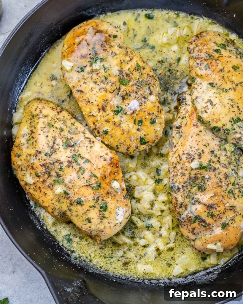 Chicken breasts in a garlic butter sauce in a round black skillet.