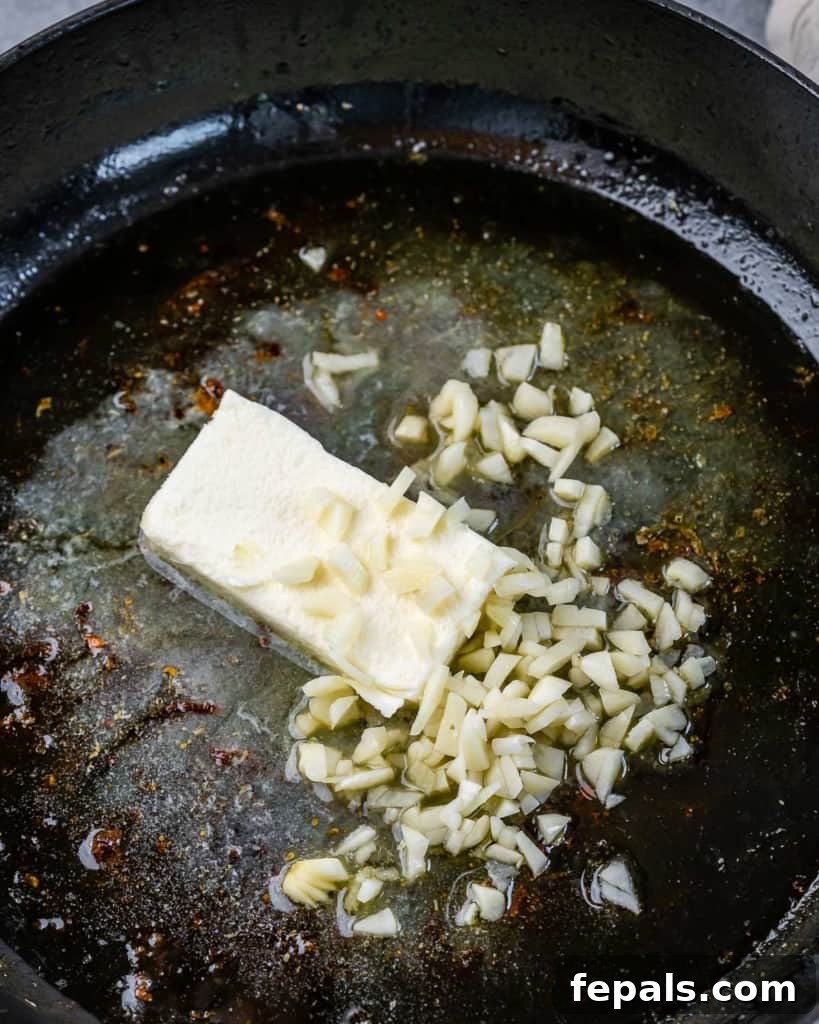 Adding broth, butter and garlic to a pan.