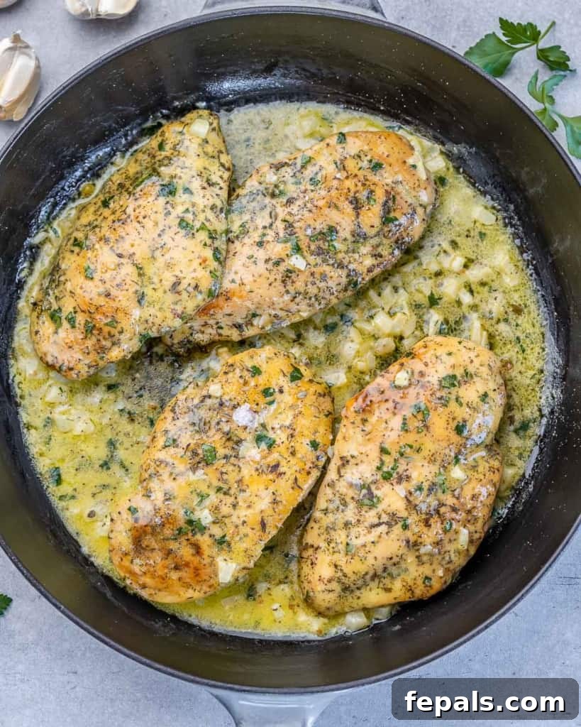Chicken breasts cooking in a garlic butter sauce.