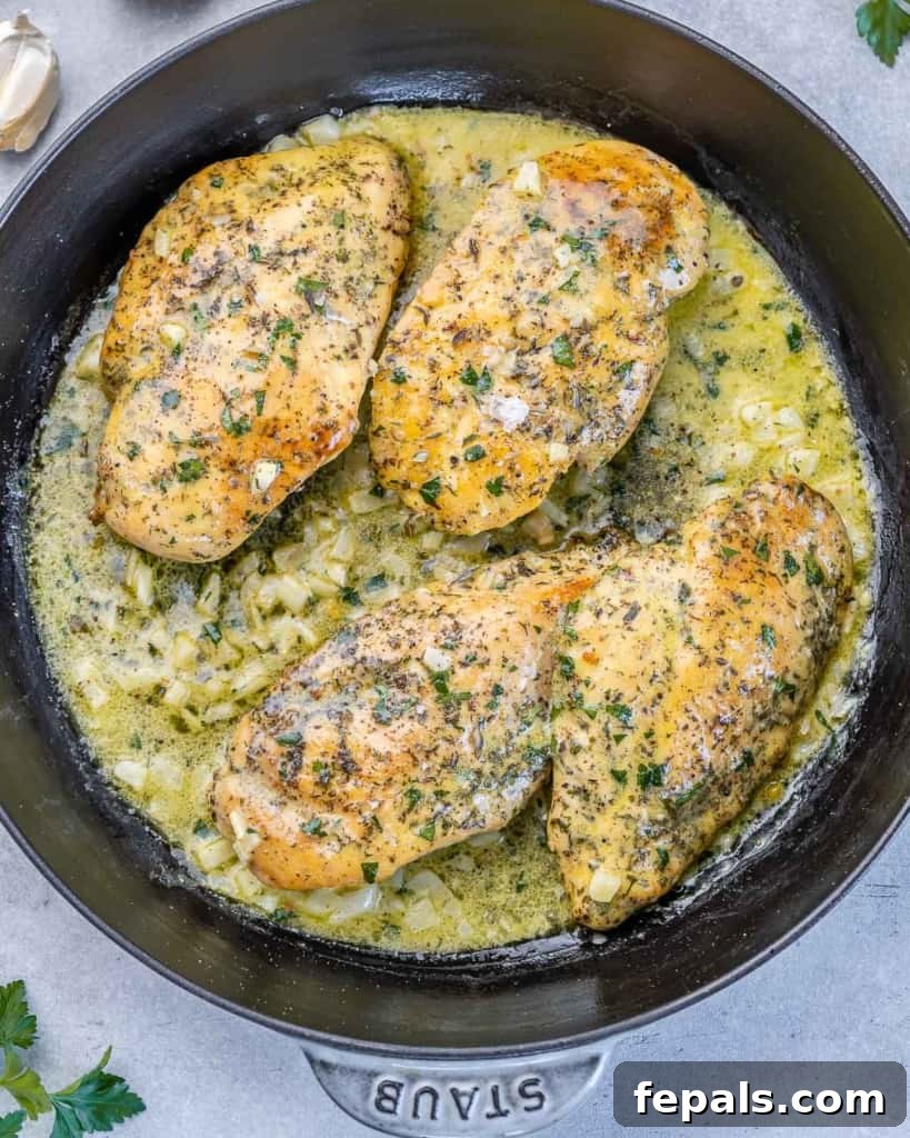 top view of black skillet with 4 chicken breasts in a garlic butter sauce 