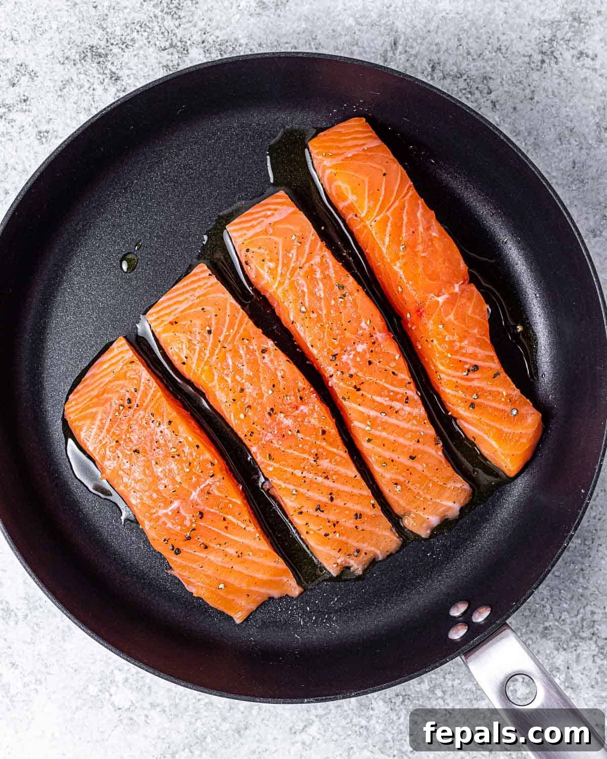 Salmon fillets being cooked in a large skillet until golden and flaky.