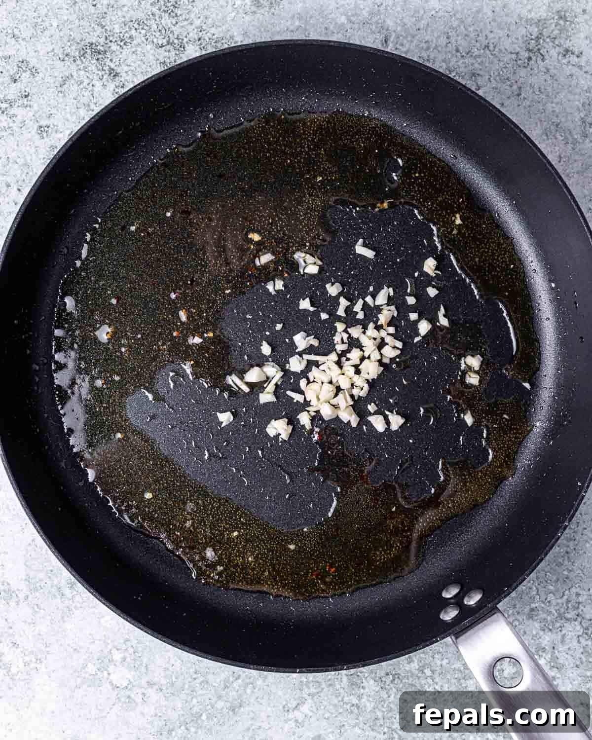 Minced garlic cloves being sautéed in the same skillet after the salmon has been removed.