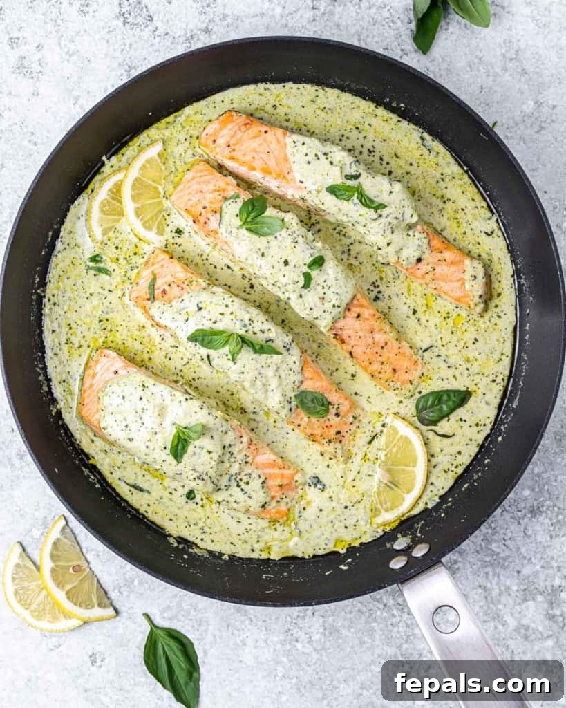 Creamy pesto salmon garnished with fresh basil and served with bright lemon wedges, ready to eat.
