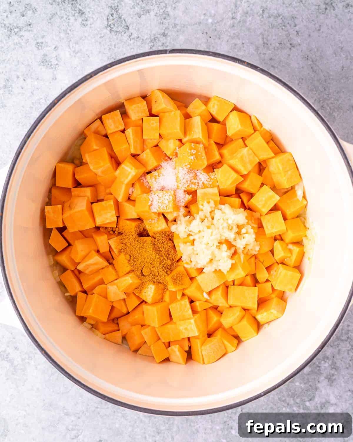 Cooking cubed sweet potato with onion, garlic, and taco seasoning in a Dutch oven.