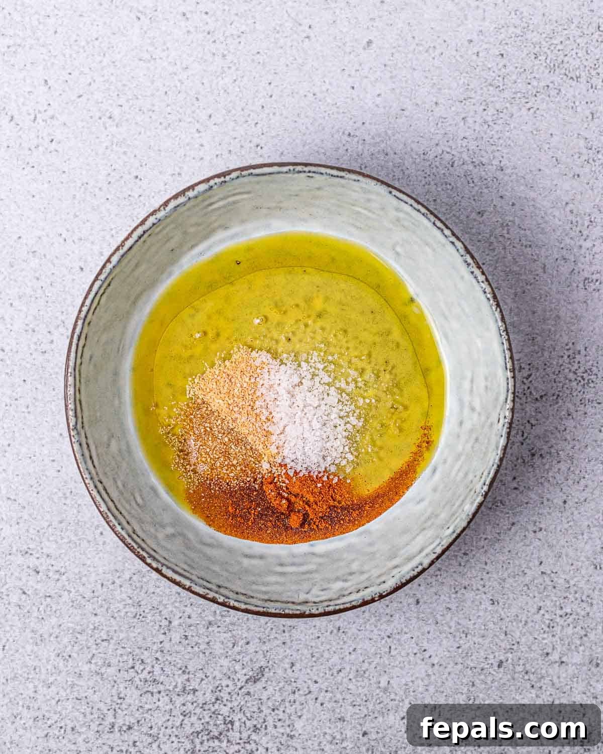Mixing seasonings with oil in a small bowl.