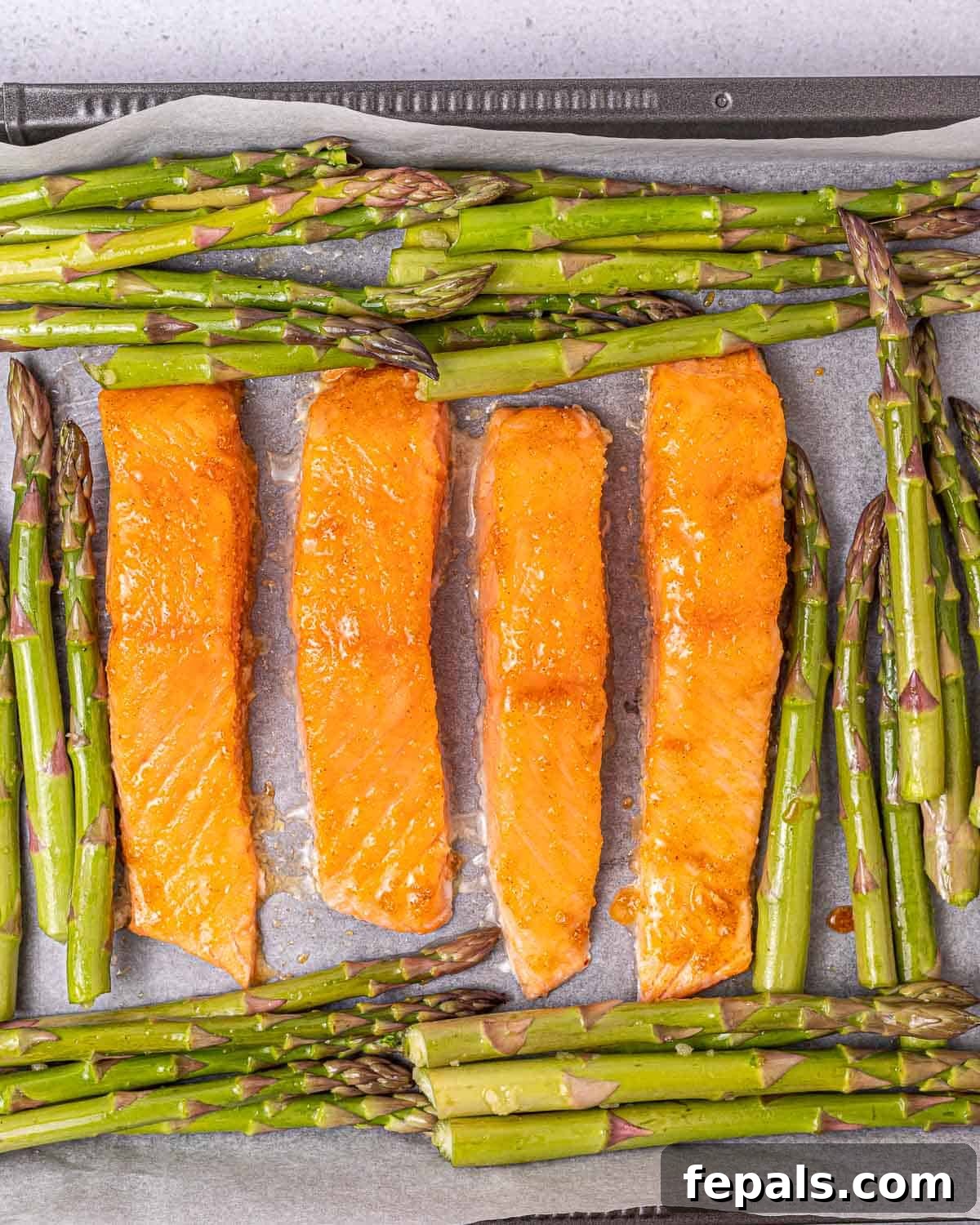 Placing salmon on a baking sheet with asparagus. 