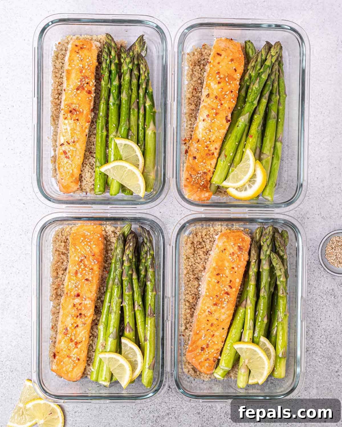 Assembling 4 bowls with salmon, asparagus, and quinoa.