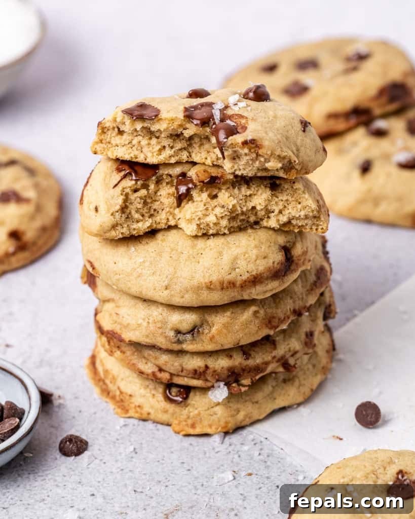 A side view of perfectly baked vegan chocolate chip cookies, stacked artfully to showcase their soft texture and abundant dairy-free chocolate chips.