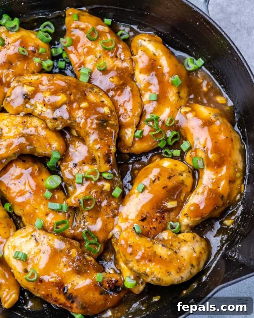 top view chicken tenders in a honey garlic sauce in black pan