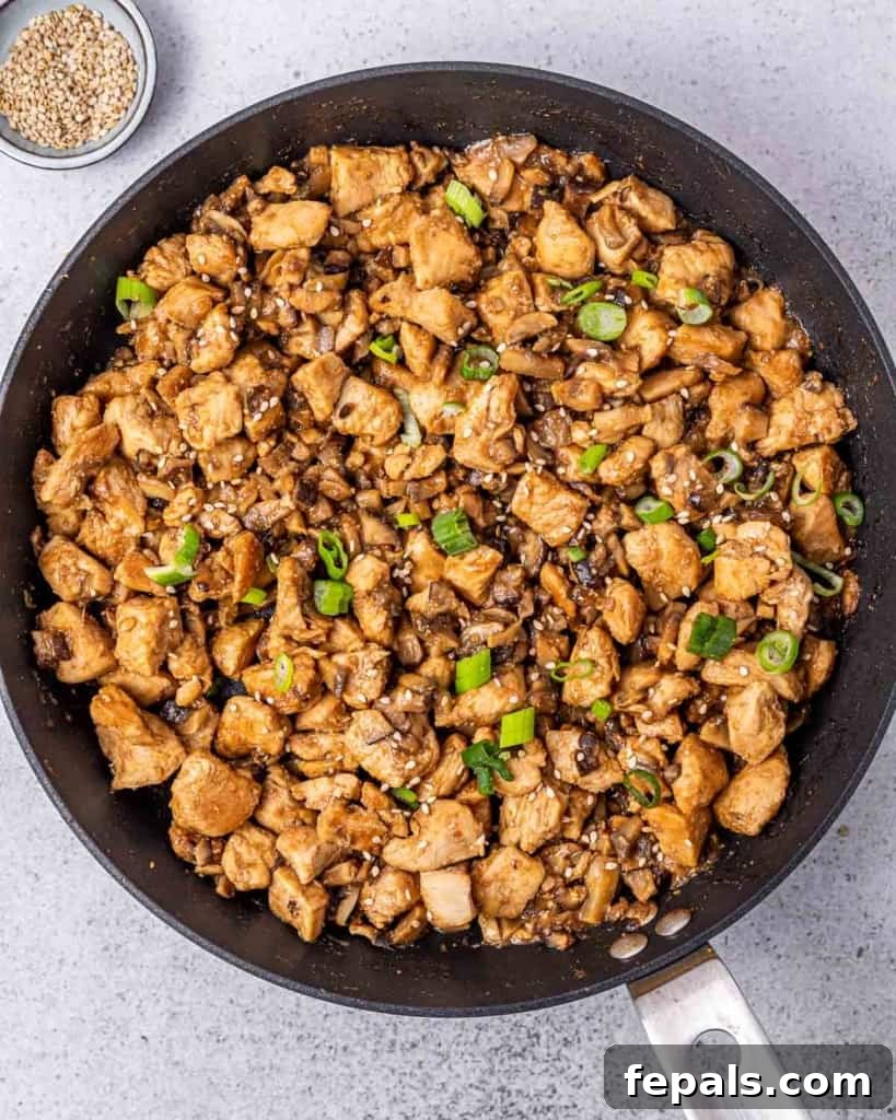 Asian chicken filling topped with green onions in a skillet.