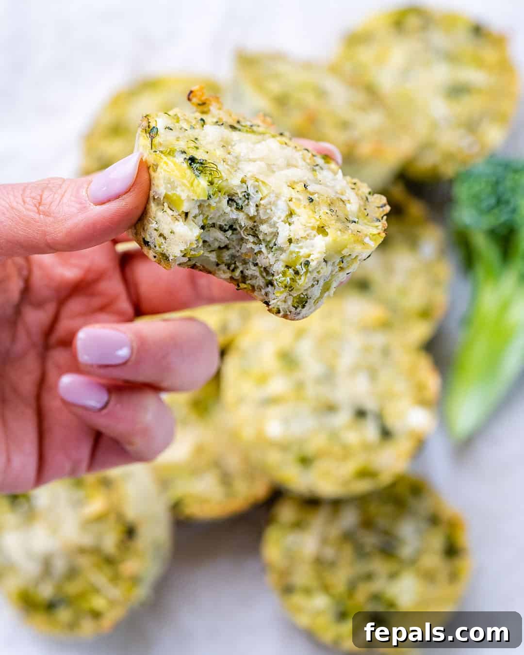 Cheesy Broccoli Quinoa Nuggets 6 Close-up of a broccoli cheddar quinoa bite held between fingers, revealing cheesy, moist filling.