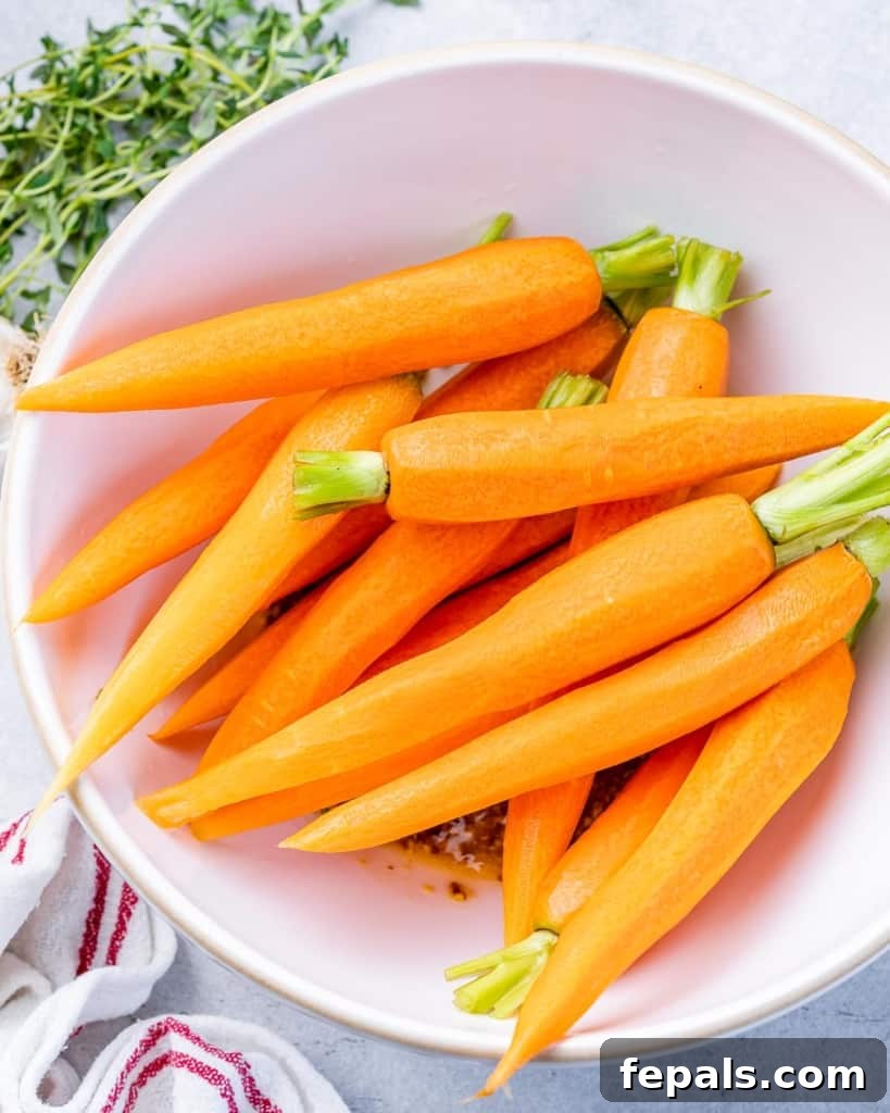 Golden Honey Mustard Carrots 5 Peeled carrots in a white bowl, ready for seasoning.