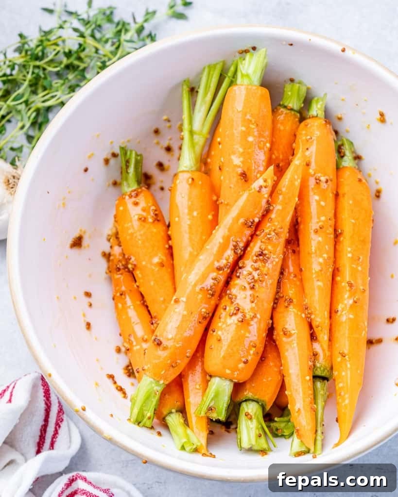 Golden Honey Mustard Carrots 7 Coating whole carrots evenly in a honey mustard sauce within a bowl.