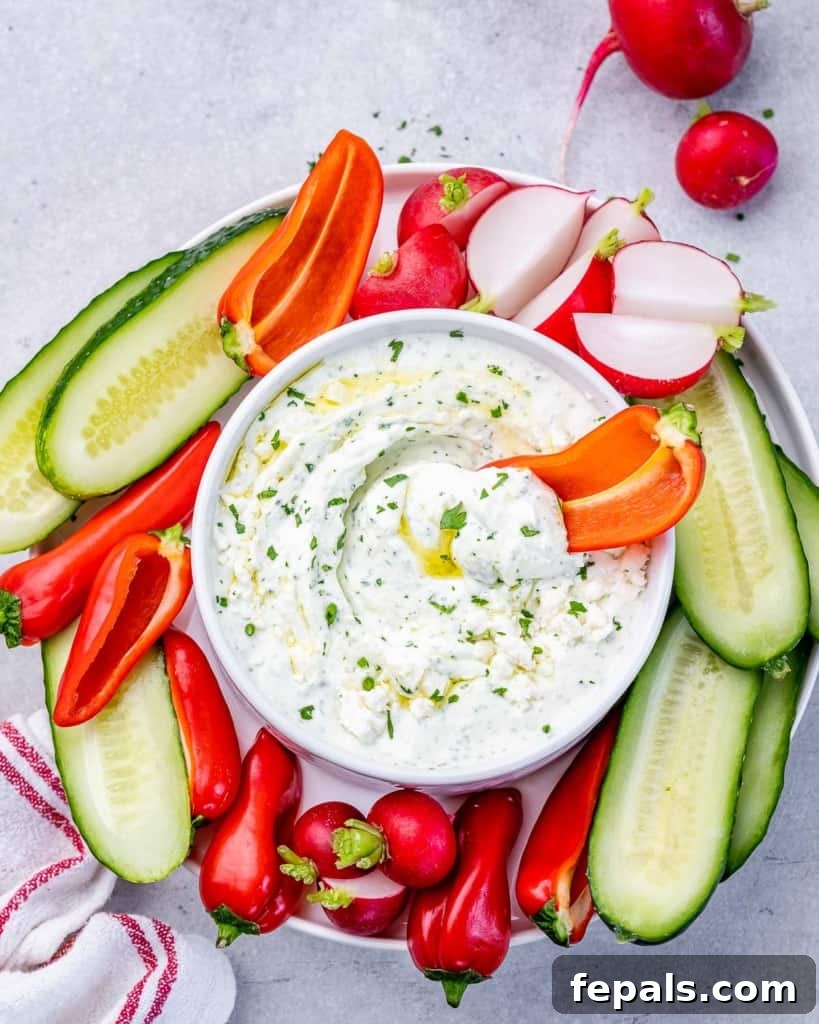A vibrant bell pepper strip, perfectly coated in the creamy herbed whipped feta dip, ready for a bite.