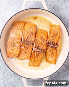 4 sauteed salmon fillets in a pan.