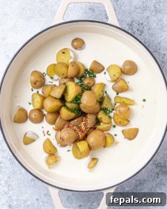 potatoes added over a creamy white sauce in skillet