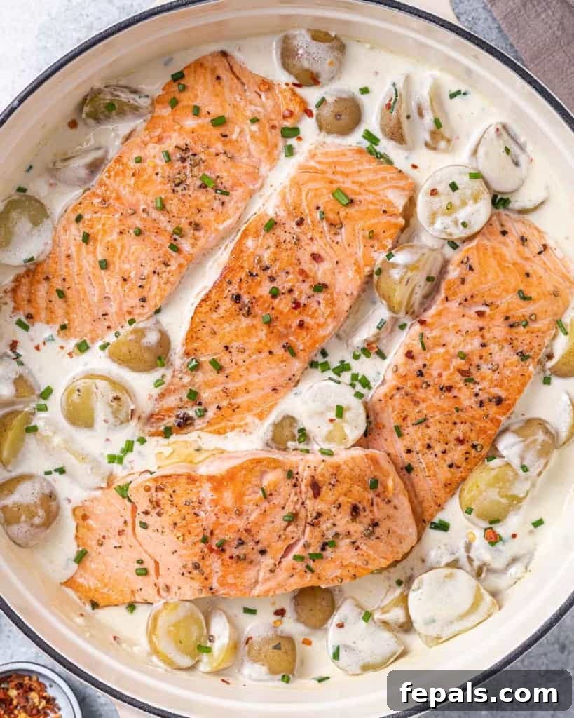 Close up shot of a salmon fillet in a skillet, coated in a luscious creamy potato sauce, highlighting its texture and inviting presentation.