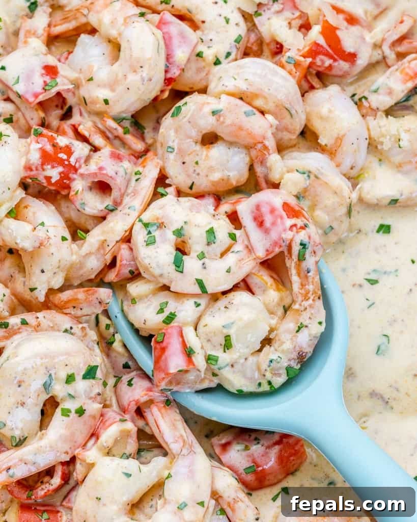 Luscious Garlic Shrimp Skillet Feast 3 A large blue serving spoon dishing out creamy garlic shrimp from an orange skillet.