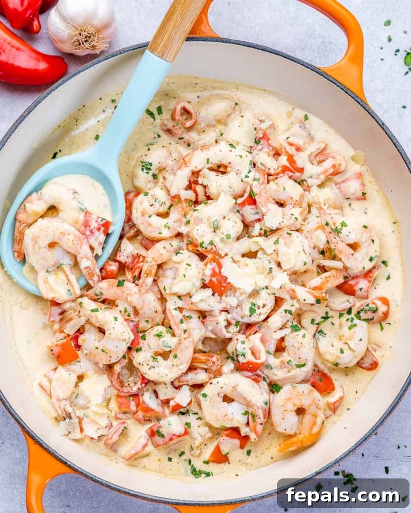Luscious Garlic Shrimp Skillet Feast 9 Top view of creamy sautéed shrimp with peppers in an orange skillet, with a baby blue serving spoon partially visible in the pan.