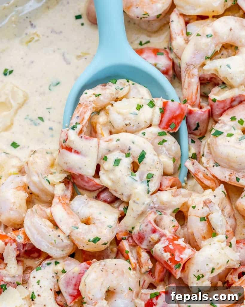 Luscious Garlic Shrimp Skillet Feast 10 Using a large blue spoon to serve creamy shrimp and peppers from a pan, showing the rich texture of the sauce.