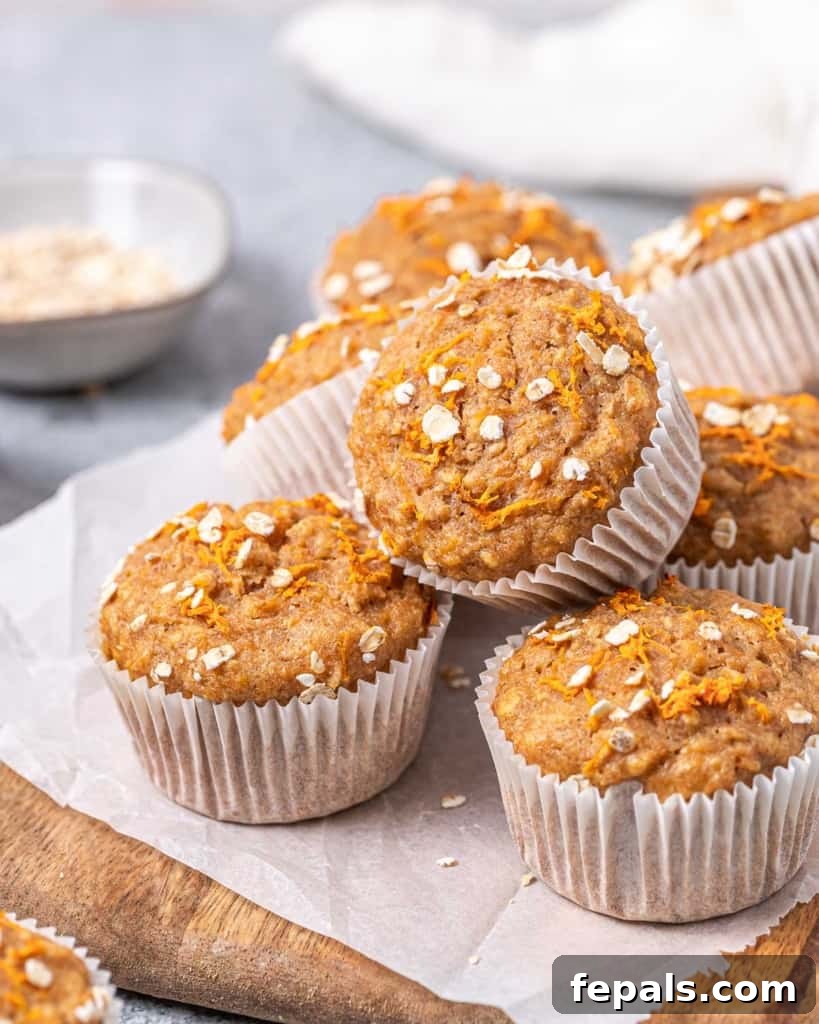 Freshly baked carrot muffins stacked on parchment paper, highlighting their tender texture.